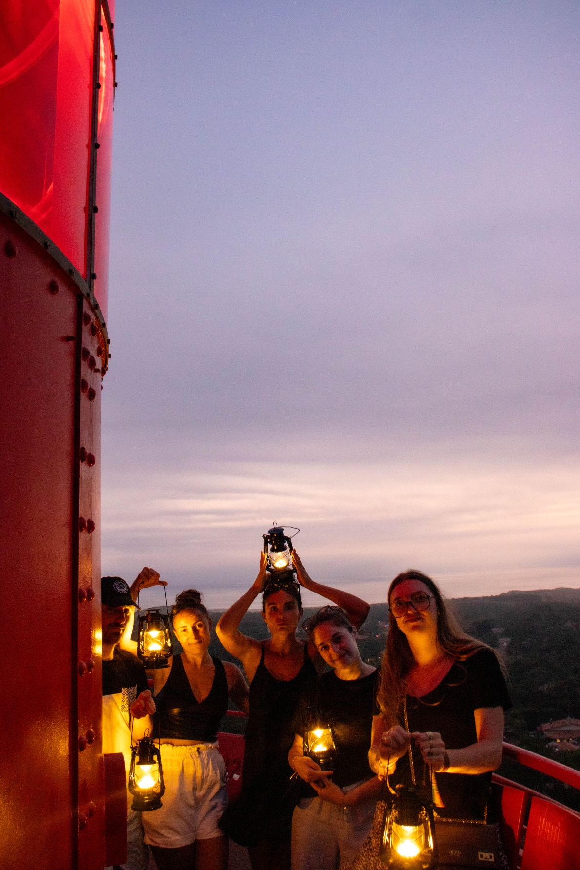 Un groupe de visiteurs profite du sommet du Phare du Cap Ferret lors des nocturnes, avec des lanternes illuminées.