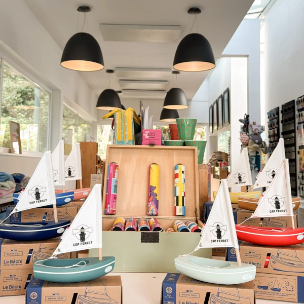 Bateaux voiliers miniatures Cap Ferret en bois colorés disponibles à la boutique du Phare du Cap Ferret - Jouets et souvenirs nautiques