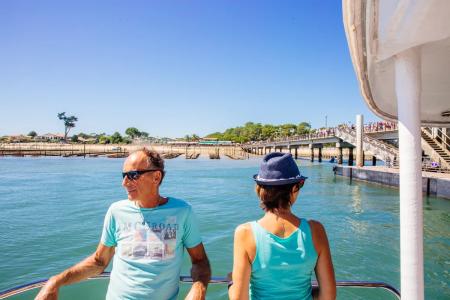 Couple de touristes sur un bateau traversant le Bassin d'Arcachon pour rejoindre la presqu'île du Cap Ferret - Traversée estivale en Gironde